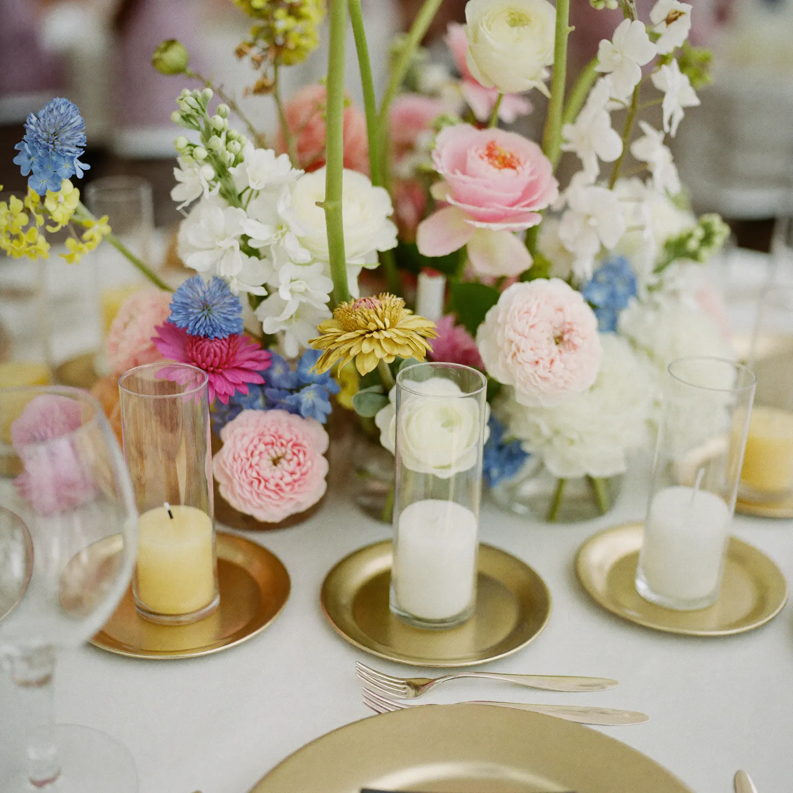 A centrepiece with candles, florals and gold chargers